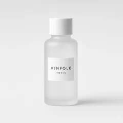 Frosted glass bottle with a white screw cap and a label reading Kinfolk tonic