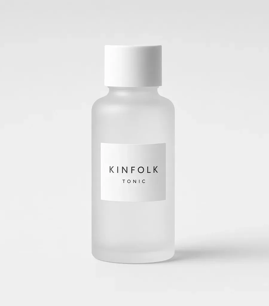 Frosted glass bottle with a white screw cap and a label reading Kinfolk tonic