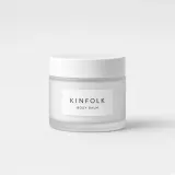 Frosted glass jar with a white lid and a label reading Kinfolk body balm
