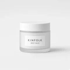 Frosted glass jar with a white lid and a label reading Kinfolk body balm