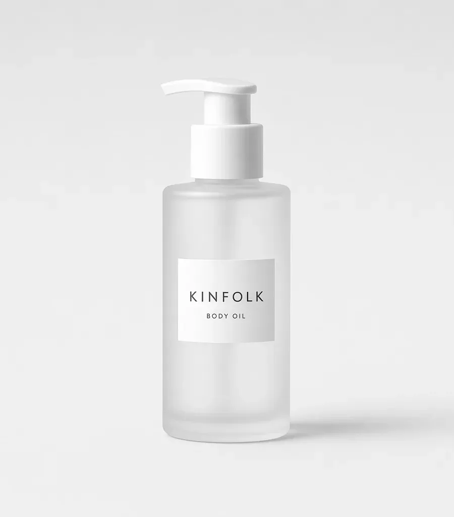 Frosted glass pump bottle with a white label reading Kinfolk body oil